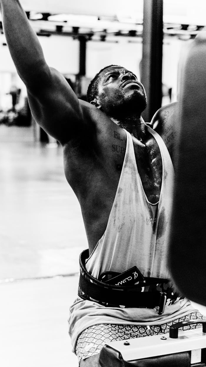 services-03 Sweaty man in gym lifting weights, showcasing intense effort and determination.