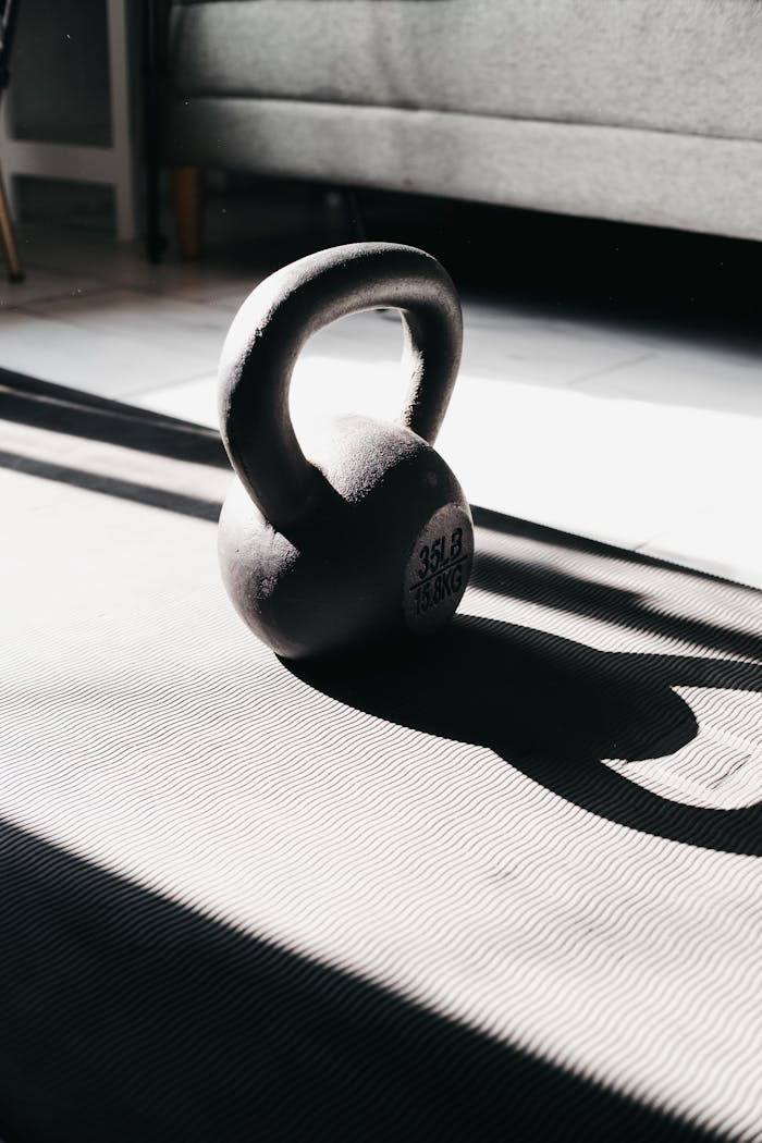 services-01 Kettlebell in bright sunlight casting shadow on gym mat indoors, perfect for fitness themes.