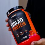 Close-up of a hand holding an Isolate Protein container in Belo Horizonte, Brazil.